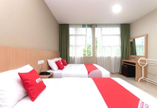 拉布安Capital O 89344 Labuan Avenue Hotel的酒店客房 - 带两张带红色枕头的床