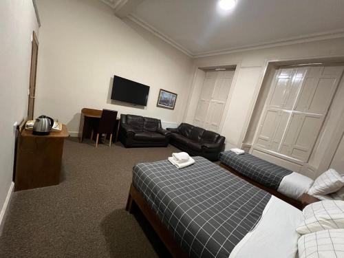 本泰兰Burntisland House的客房设有两张床、一张沙发和一台电视。