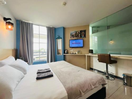 巴生海豚酒店 的一间卧室配有一张床、一张书桌和一台电视
