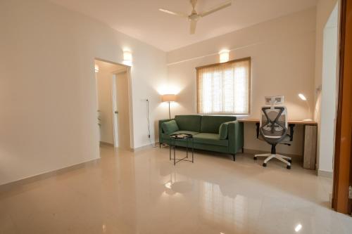 班加罗尔HomeSlice Whitefield - 1BHK, 2BHK Apartment的客厅配有绿色沙发和椅子