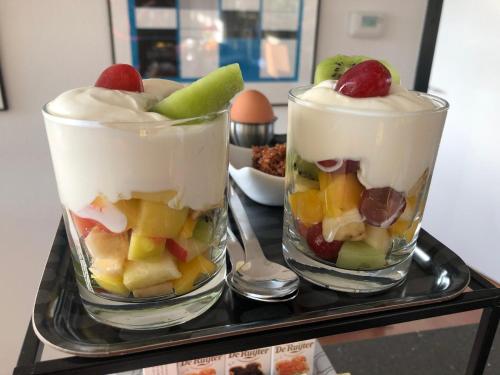 埃曼BEDbijPET的托盘上装满水果和奶油的两杯