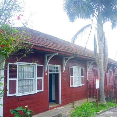 巴拉那皮亚卡巴Pousada Maranata B&B的前面有棕榈树的红色房子