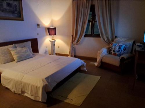 雅温得Village NDJIKESSI的一间卧室配有一张大床和一把椅子
