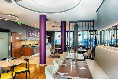 美因河畔法兰克福Premier Inn Frankfurt City Europaviertel的餐厅设有紫色柱子和桌椅