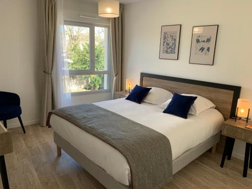里摩日Domitys Villa Kera的一间卧室配有一张带蓝色枕头的床和一扇窗户。
