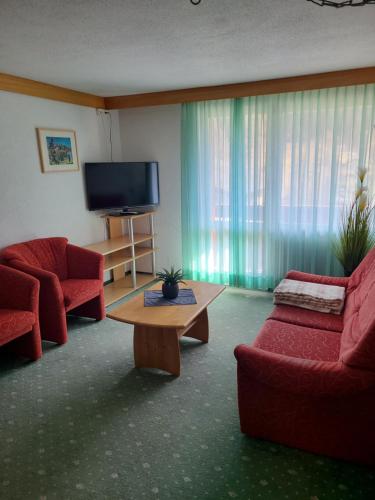 格林德尔瓦尔德里斯登公寓酒店的客厅配有2把红色椅子和平面电视