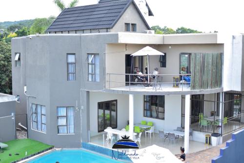 内尔斯普雷特Naldorado Executive Villa的一座带游泳池的房子,人们坐在阳台上