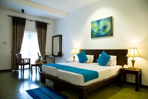 卡卢特勒Rathna Beach Wadduwa的一间卧室配有一张带蓝色枕头的大床