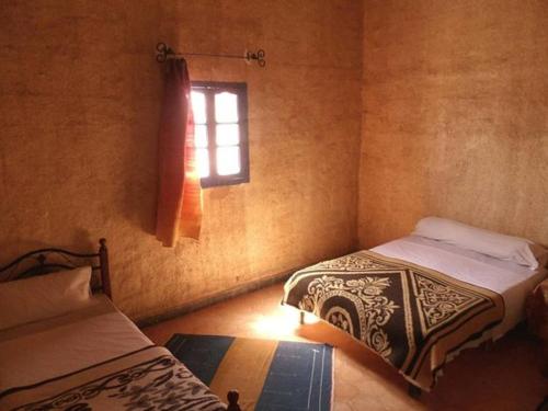 梅尔祖卡Hostel la palmeraie merzouga的一间卧室设有两张床和窗户。