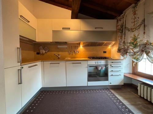 维罗纳Piazza Erbe Lodge的厨房配有白色橱柜和炉灶。