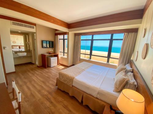 福塔莱萨Magna Praia Hotel的一间卧室设有一张大床,享有海景