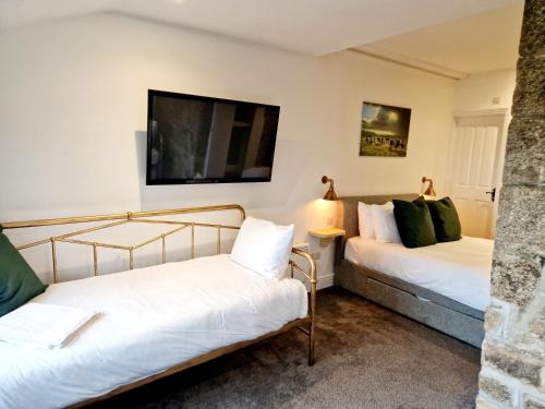 利斯卡德Wheal Tor Hotel & Glamping的一间卧室设有两张床,墙上配有电视。