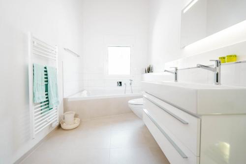 艾姆敦Apartment Soldanella的白色的浴室设有浴缸和水槽。