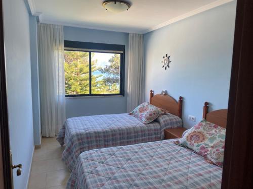 福斯特拉Apartamentos Playa Langosteira的一间卧室设有两张床和窗户。