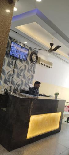 新德里gold stays hotel near IGI international airport的坐在墙上挂着时钟的房间的人