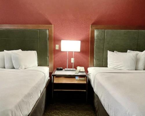 韦恩堡FairBridge Inn & Suites Fort Wayne的酒店客房设有两张床和一张带台灯的桌子。