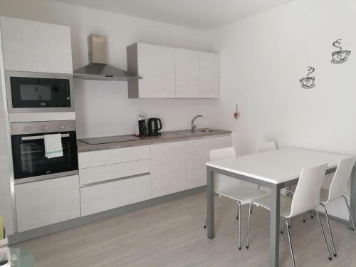 阿科Appartamento Meridiana的厨房配有白色橱柜和桌椅