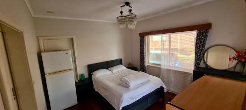 诺瑟姆Charming Brick Homestay Room in Northam的卧室配有白色的床和冰箱。