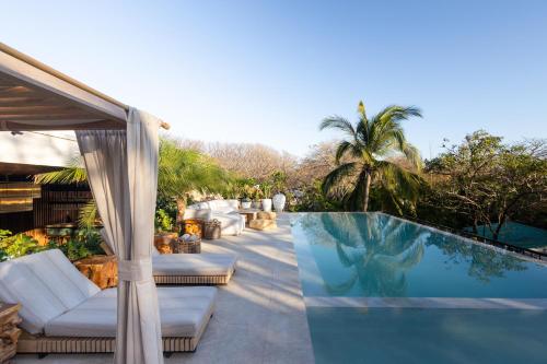 诺萨拉Silvestre Nosara Hotel & Residences的一座房子旁的带白色家具的游泳池