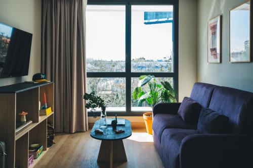 马德里The Oliver Apartamentos Aravaca的客厅设有蓝色的沙发和大窗户