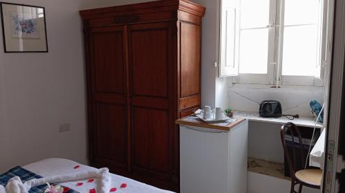 科斯皮夸Corto Maltese Guest House的卧室设有大型木制橱柜,靠窗