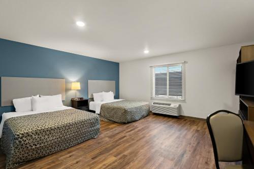 柯林斯堡WoodSpring Suites Fort Collins的酒店客房设有两张床和电视。