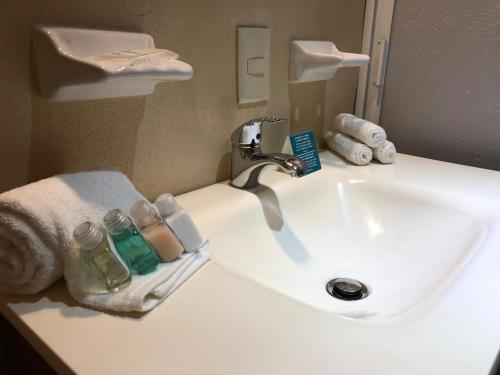萨尤利塔Pacific Inn hotel的白色浴室水槽、水龙头和毛巾