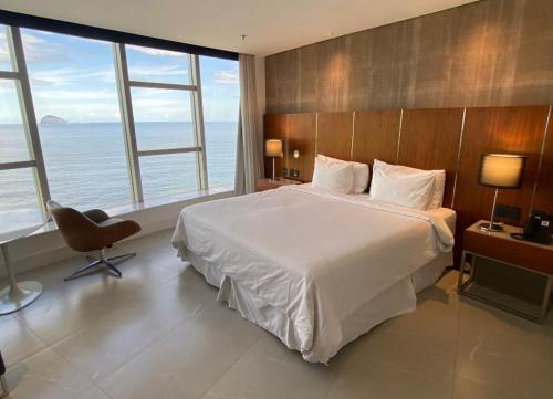 里约热内卢Apart Hotel的一间卧室配有一张床、一把椅子和窗户。