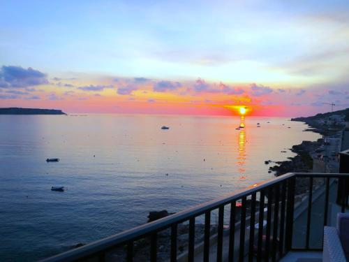 梅利哈Seafront apartment Terrace, lounger & Panoramic ocean views的船在水体上日落