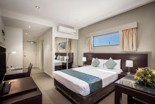 艾利斯斯普林斯Quest Alice Springs的酒店客房设有一张大床和一张书桌。