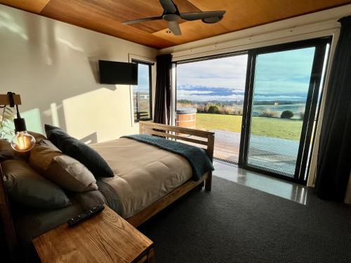 蒂阿瑙Fiordland Eco-Retreat -- Panoramic Views -- Hot Tub的一间卧室设有一张床和一个大型滑动玻璃门