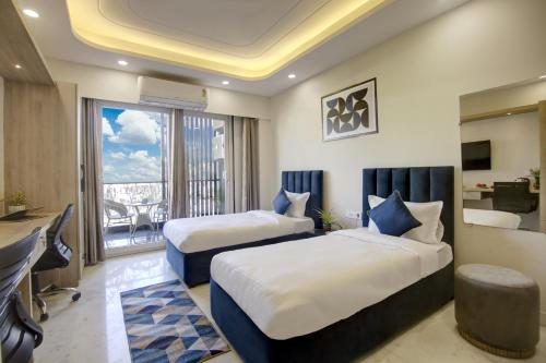古尔冈FlxHo Quad - Luxury Studio Apart Hotel DLF Cyber City的酒店客房设有两张床和一个阳台。