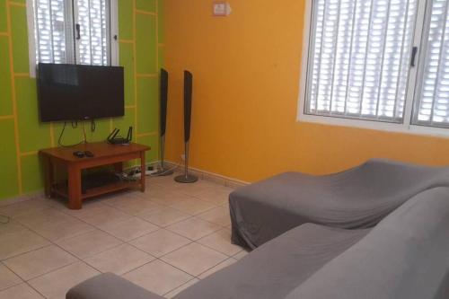 罗安达Casa de Amor的客厅配有平面电视和桌子。