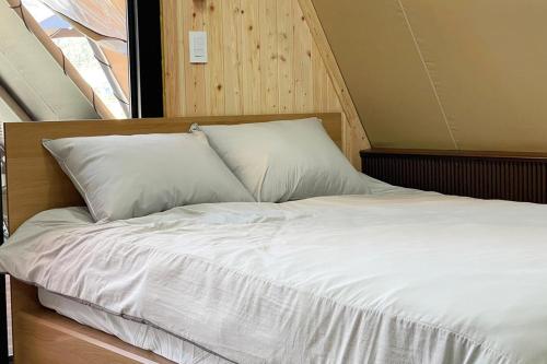 抱川市Pocheon Artemis Glamping的一张带白色床单和枕头的床