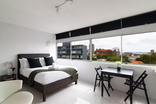 悉尼Studio with Stunning Views and Free Parking的一间卧室配有一张床、一张桌子和一个窗户。