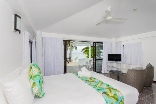 拉罗汤加贝拉海滩简易别墅酒店的一间白色的卧室,配有床和客厅