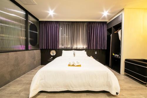 晋州市Epoche Hotel的紫色窗帘的房间一张大白色的床