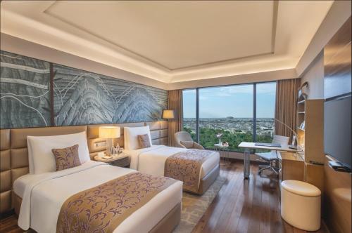 新德里新德里利拉格调会议酒店的酒店客房设有两张床、一张书桌和一个窗户。