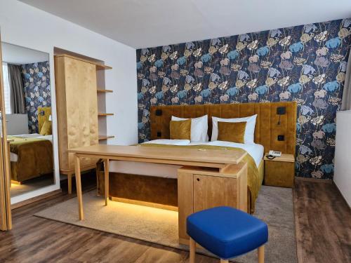 多瑙河畔克雷姆斯科林胡伯加斯特霍夫酒店的一间卧室配有一张床和一张带蓝色凳子的书桌