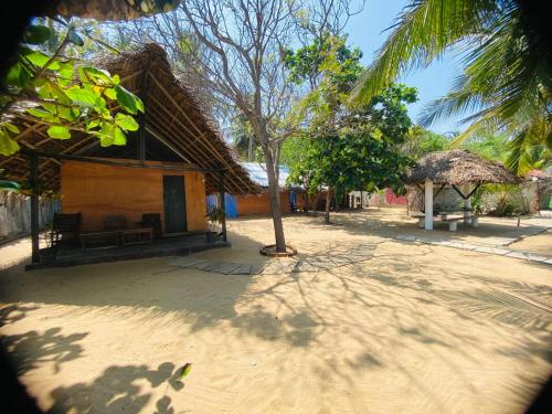 阿鲁甘湾Rainbow Village Cabanas的海滩上带草屋顶的小房子