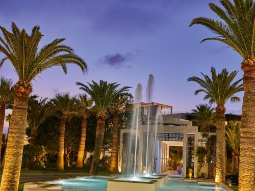 罗希姆诺格雷科泰克雷塔皇庭酒店的棕榈树建筑前的喷泉