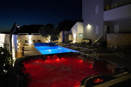 伊穆尼Villa Olea的游泳池在晚上设有红色浴缸