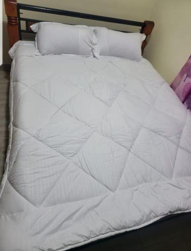 BungomaEbeneza的一张带白色床单和枕头的床