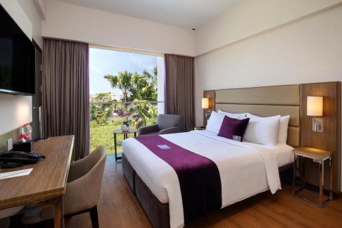 诗都阿佐Premier Place Surabaya Airport的酒店客房设有一张大床和一张书桌。