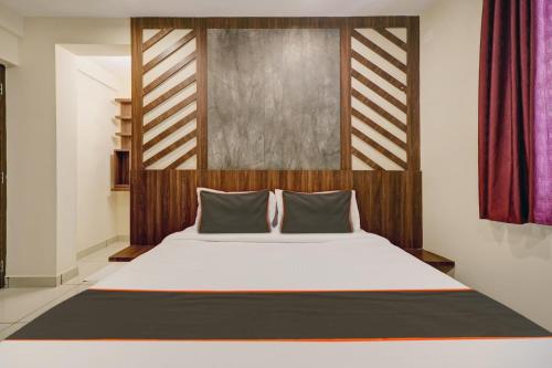 科钦GYPSY HOTEL CUSAT的一间卧室配有一张大床和木制床头板