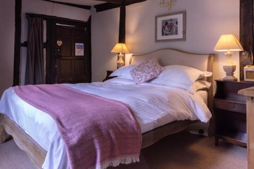 拉科克天使神迹宾馆的一间卧室配有一张大床和紫色毯子