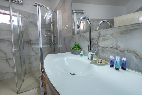 Yarkaוילה ריש - מושלמת למשפחות עם בריכה, ג'קוזי ונוף的浴室配有白色水槽和淋浴。