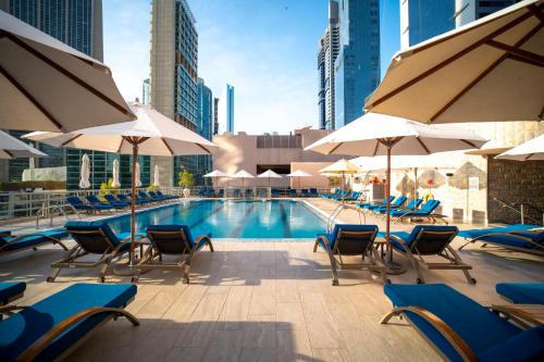 迪拜迪拜瑞汉金玫瑰罗塔纳酒店的一个带椅子和遮阳伞的游泳池
