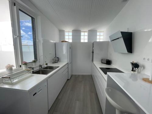 宏达海滩White Serenity的白色的厨房配有白色的柜台和大窗户