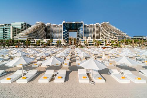 迪拜迪拜朱美拉五棕榈度假酒店的沙滩上一大群白色的遮阳伞